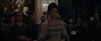 Movie still from “Fantastic Beasts: The Secrets of Dumbledore” (2022), directed by David Yates – A woman standing in front of a group of people; Medium shot, Over the shoulder angle