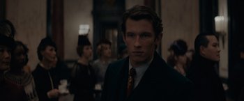 Movie still from “Fantastic Beasts: The Secrets of Dumbledore” (2022), directed by David Yates – A man wearing a suit and tie standing in front of a crowd; Close Up shot, Over the shoulder angle