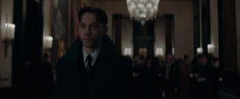 Movie still from “Fantastic Beasts: The Secrets of Dumbledore” (2022), directed by David Yates – A man wearing a suit and tie in a room; Close Up shot, Low angle