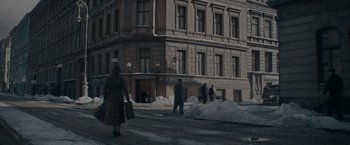 Movie still from “Fantastic Beasts: The Secrets of Dumbledore” (2022), directed by David Yates – A group of people walking down a street near a building; Extreme Wide shot, High angle