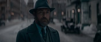 Movie still from “Fantastic Beasts: The Secrets of Dumbledore” (2022), directed by David Yates – A man with a beard wearing a hat and a suit; Close Up shot, Low angle
