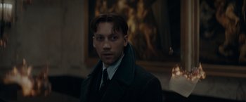 Movie still from “Fantastic Beasts: The Secrets of Dumbledore” (2022), directed by David Yates – A man wearing a suit and tie in front of a painting; Close Up shot, Low angle