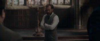 Movie still from “Fantastic Beasts: The Secrets of Dumbledore” (2022), directed by David Yates – A man standing in front of an owl statue; Medium shot, Low angle