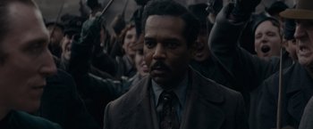 Movie still from “Fantastic Beasts: The Secrets of Dumbledore” (2022), directed by David Yates – A group of people standing next to each other in a crowd; Close Up shot, Over the shoulder angle