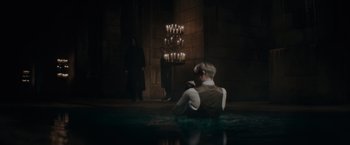 Movie still from “Fantastic Beasts: The Secrets of Dumbledore” (2022), directed by David Yates – A man sitting on the ground in front of candles; Wide shot, High angle