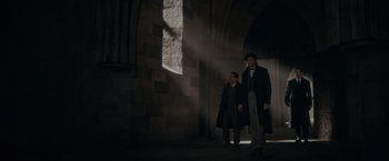 Movie still from “Fantastic Beasts: The Secrets of Dumbledore” (2022), directed by David Yates – A man and a woman standing next to each other in front of a stone wall; Wide shot, Low angle