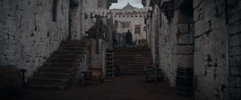 Movie still from “Fantastic Beasts: The Secrets of Dumbledore” (2022), directed by David Yates – A man standing on a set of stairs in the middle of a building; Extreme Wide shot, High angle