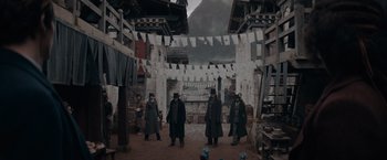 Movie still from “Fantastic Beasts: The Secrets of Dumbledore” (2022), directed by David Yates – A group of men standing on a dirt road; Wide shot, High angle