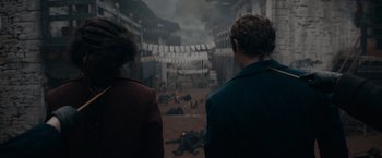 Movie still from “Fantastic Beasts: The Secrets of Dumbledore” (2022), directed by David Yates – Two people are looking at the dead bodies in the street; Medium shot, High angle