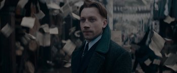 Movie still from “Fantastic Beasts: The Secrets of Dumbledore” (2022), directed by David Yates – A man in a suit and tie standing in front of a wall; Close Up shot, Over the shoulder angle