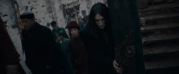 Movie still from “Fantastic Beasts: The Secrets of Dumbledore” (2022), directed by David Yates – A group of people walking down a street; Medium shot, High angle