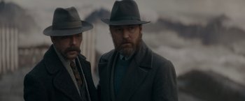 Movie still from “Fantastic Beasts: The Secrets of Dumbledore” (2022), directed by David Yates – A man in a hat and a coat and a man in a tie; Medium shot, Low angle