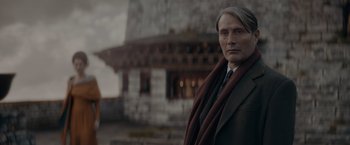 Movie still from “Fantastic Beasts: The Secrets of Dumbledore” (2022), directed by David Yates – A man wearing a suit and tie standing in front of a building; Close Up shot, Low angle