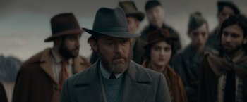 Movie still from “Fantastic Beasts: The Secrets of Dumbledore” (2022), directed by David Yates – A man in a hat and a gray coat; Close Up shot, Over the shoulder angle