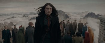 Movie still from “Fantastic Beasts: The Secrets of Dumbledore” (2022), directed by David Yates – A man with long black hair standing in front of a group of people; Medium shot, Low angle