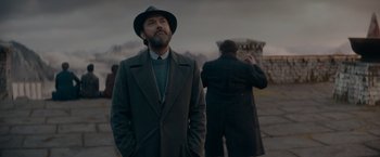 Movie still from “Fantastic Beasts: The Secrets of Dumbledore” (2022), directed by David Yates – A man with a beard wearing a hat and a coat; Medium shot, Low angle