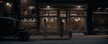 Movie still from “Fantastic Beasts: The Secrets of Dumbledore” (2022), directed by David Yates – A man and a woman standing in front of a store; Extreme Wide shot, Over the shoulder angle
