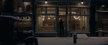 Movie still from “Fantastic Beasts: The Secrets of Dumbledore” (2022), directed by David Yates – A person standing in front of a store on a snowy day; Wide shot, Over the shoulder angle
