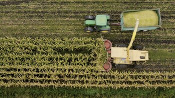 Movie still from “Fantastic Fungi” (2019), directed by Louie Schwartzberg – An aerial view of a tractor pulling a trailer in a field; Extreme Wide shot, Overhead angle