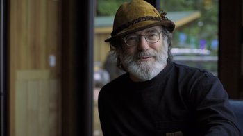 Movie still from “Fantastic Fungi” (2019), directed by Louie Schwartzberg – An older man wearing a hat and glasses; Close Up shot, Over the shoulder angle