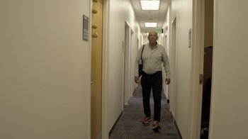 Movie still from “Fantastic Fungi” (2019), directed by Louie Schwartzberg – An older man is walking down a long hallway; Wide shot, Low angle