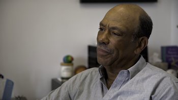 Movie still from “Fantastic Fungi” (2019), directed by Louie Schwartzberg – An older man sitting in front of a television; Close Up shot, Over the shoulder angle