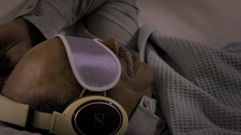 Movie still from “Fantastic Fungi” (2019), directed by Louie Schwartzberg – A dog laying on top of a bed with a pair of headphones; Close Up shot, Overhead angle