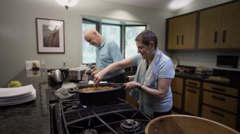 Movie still from “Fantastic Fungi” (2019), directed by Louie Schwartzberg – Two people in a kitchen preparing a meal; Wide shot, Low angle