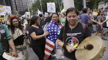 Movie still from “Fantastic Fungi” (2019), directed by Louie Schwartzberg – A group of people marching down a street; Medium shot, High angle