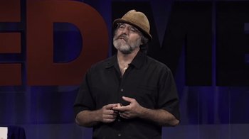 Movie still from “Fantastic Fungi” (2019), directed by Louie Schwartzberg – A man wearing a hat standing in front of a microphone; Close Up shot, Low angle