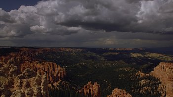 Movie still from “Fantastic Fungi” (2019), directed by Louie Schwartzberg – A view of a mountain range with dark clouds in the background; Extreme Wide shot, High angle