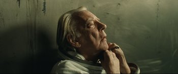 An old man with a white beard is looking up