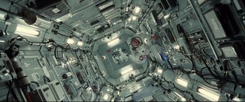 Movie still from “Ad Astra” (2019), directed by James Gray – An overhead view of a person in a space station; Wide shot, Overhead angle