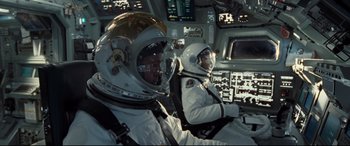 Movie still from “Ad Astra” (2019), directed by James Gray – Two men in spacesuits are sitting in the cockpit of an airplane; Medium shot, Overhead angle