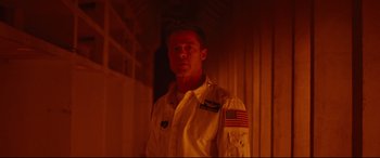 Movie still from “Ad Astra” (2019), directed by James Gray – A man wearing a uniform with an american flag on it; Medium shot, Low angle
