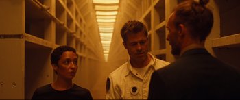 Movie still from “Ad Astra” (2019), directed by James Gray – A group of people standing around in a hallway; Medium shot, Over the shoulder angle