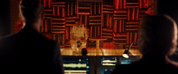 Movie still from “Ad Astra” (2019), directed by James Gray – A man sitting on a chair in front of a wall of books; Wide shot, Over the shoulder angle