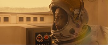 Movie still from “Ad Astra” (2019), directed by James Gray – A woman wearing a space suit and helmet in front of a control panel; Medium shot, Low angle
