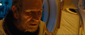 Movie still from “Ad Astra” (2019), directed by James Gray – An old man with a beard and a white shirt is looking at the camera; Close Up shot, Low angle