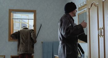 Movie still from “Fargo” (1996), directed by Ethan Coen – A man in a leather jacket and a black hat is putting on a jacket; Medium shot, Over the shoulder angle