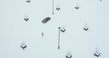 Movie still from “Fargo” (1996), directed by Ethan Coen – An aerial view of a person walking in the snow near a parked car; Extreme Wide shot, Overhead angle