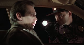 Movie still from “Fargo” (1996), directed by Ethan Coen – A police officer looking at a man in a car mirror; Close Up shot, Low angle