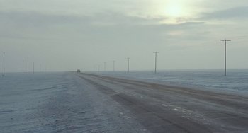 Movie still from “Fargo” (1996), directed by Ethan Coen – An empty road in the middle of a snowy field; Extreme Wide shot, High angle