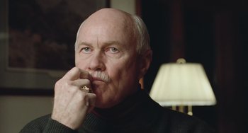 Movie still from “Fargo” (1996), directed by Ethan Coen – An older man with a beard and a mustache is holding his hand to his face; Close Up shot, Low angle