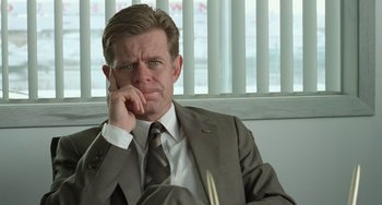 Movie still from “Fargo” (1996), directed by Ethan Coen – A man wearing a suit and tie holding his hand to his face; Close Up shot, Low angle