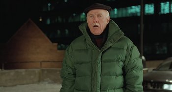 Movie still from “Fargo” (1996), directed by Ethan Coen – An older man wearing a green jacket and a black hat; Medium shot, Over the shoulder angle