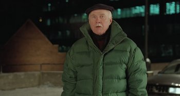 Movie still from “Fargo” (1996), directed by Ethan Coen – An older man wearing a green jacket and a black hat; Medium shot, Over the shoulder angle