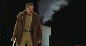 Movie still from “Fargo” (1996), directed by Ethan Coen – A man in a brown jacket standing in front of a smoke stack; Medium shot, Low angle