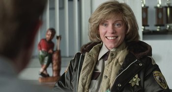 Movie still from “Fargo” (1996), directed by Ethan Coen – A woman in a brown jacket smiling for the camera; Close Up shot, Over the shoulder angle