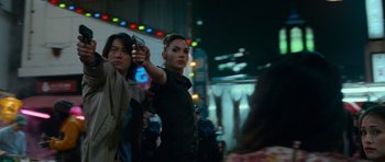 Movie still from “Fast & Furious 6” (2013), directed by Justin Lin – A woman is holding a bottle in her hand while standing next to a man; Medium shot, Low angle